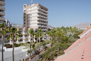 a tall white building with palm trees in front of it at Melo sur in Playa de las Americas
