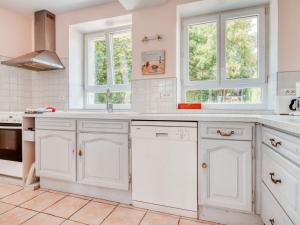 a white kitchen with white cabinets and windows at Cozy Farm House in Boncourt with Barbeque in Sainte-Preuve