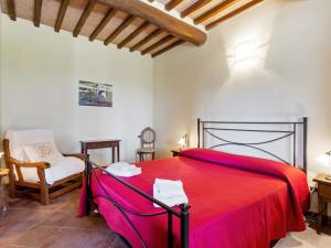 um quarto com uma cama vermelha e uma cadeira em Belvilla by OYO Casa Sugheri em Suvereto