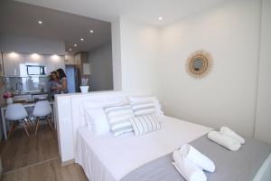 a white bedroom with a white bed and a kitchen at Lakones Deluxe Suites in Lákones