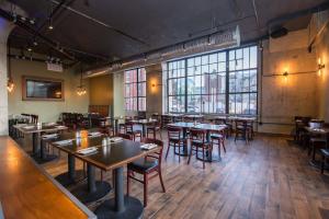 un restaurante con mesas y sillas de madera y ventanas grandes en Sosuite at Independence Lofts - Callowhill, en Filadelfia