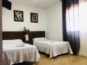 2 camas en una habitación con 2 mesas en Hostal Restaurante EL AVION S,L, en Villar de Plasencia