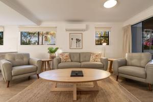 a living room filled with furniture and a table at Gosamara Apartments in Byron Bay