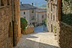 um beco numa cidade velha com edifícios de pedra em Casa Rural Cal Met em Sant Boi de Lluçanès