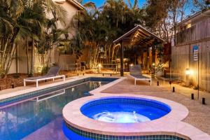a swimming pool with a patio and a house at Gosamara Apartments in Byron Bay