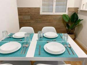 a dining table with white plates and silverware on it at Apartamento Centro Costa de la Luz in Sanlúcar de Barrameda +12 photos