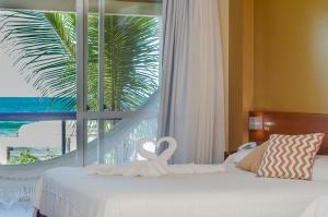 Un dormitorio con una cama y una ventana con una palmera en Pousada Garatéia, en Bombinhas