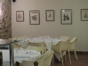 uma sala de jantar com mesas brancas e cadeiras brancas em Hotel Santa Anna em L'Estartit