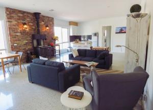 a living room with blue couches and a brick wall at Rooks Edge in Gisborne