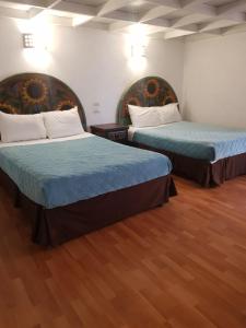 two beds in a room with wood floors at Hotel Meson Mariano Matamoros in Querétaro