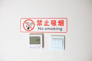 北京Beijing Xingshe Youth Hostel--Nearby Tiananmen square & Forbidden City & Houhai Bar street--1 minute walk to subway, Cat-keeping, Great wall&Forbidden city one day tour, Wifi and laundry room, English speaking Reception的墙上的标志,表示禁止吸烟