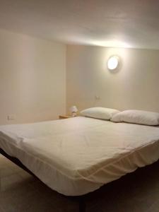 1 cama blanca grande con luz en la pared en Appartamento Rosati, en Oliveri
