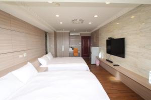 a hotel room with two beds and a flat screen tv at Sea Keelung 61 in Keelung