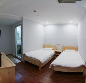 北京Beijing Xingshe Youth Hostel--Nearby Tiananmen square & Forbidden City & Houhai Bar street--1 minute walk to subway, Cat-keeping, Great wall&Forbidden city one day tour, Wifi and laundry room, English speaking Reception的两张床在铺有木地板的房间里 更多37张照片