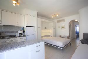 een keuken met een bed en een keuken met witte kasten bij Apartamento Casa Stella con piscina by costablancarent in Denia