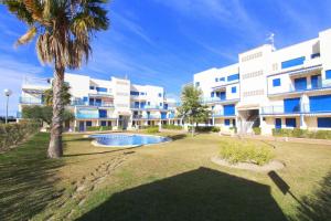 a large building with a palm tree in front of it at Duplex Marina Golf B5 by costablancarent in Oliva