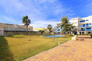 a park in front of a building with a pool at Duplex Marina Golf B5 by costablancarent in Oliva