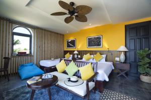 a hotel room with two beds and a couch at G Boutique Resort Hoi An in Hoi An