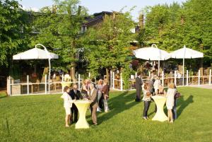 eine Gruppe von Menschen, die um Tische im Gras stehen in der Unterkunft Hotel Robben in Bremen