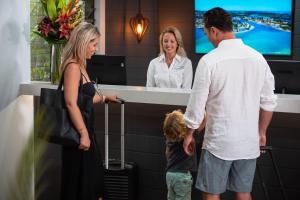 un hombre, una mujer y un niño parados frente a un mostrador en Ocean Breeze Resort, en Noosa Heads