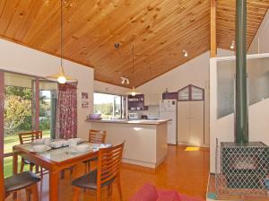 a kitchen and dining room with a table and chairs at Carefree at Cooks - Cooks Beach Bach in Cooks Beach