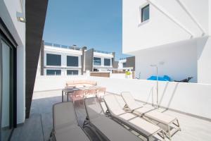 205 Luxury Gran Villa - Alicante Holiday في غران ألاكانت: شرفة مع كراسي وطاولة على مبنى