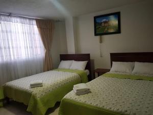 Dos camas en una habitación de hotel con toallas. en Hotel Venecia Confort, en Pasto