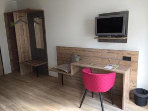 a room with a desk with a tv and a pink chair at Hotel am Kunnerstein in Augustusburg