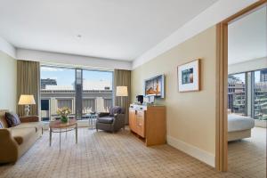 ein Wohnzimmer mit einem Sofa und einem Schreibtisch in einem Hotelzimmer in der Unterkunft The Fullerton Hotel Sydney in Sydney