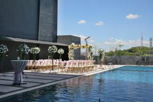 um grupo de mesas e cadeiras junto a uma piscina em Geno Hotel Shah Alam em Shah Alam