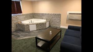 baño con bañera, mesa y sofá en Skyview Motor Inn, en Johnston