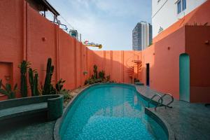 a swimming pool next to a building with a red wall at La Memoria Hotel - City Centre in Ho Chi Minh City +47 photos