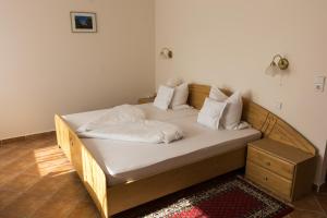 Una cama con sábanas blancas y almohadas. en Hotel Harka en Harkány
