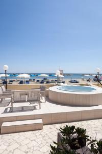 a patio with benches and a pool and the beach at Hotel Primavera sul mare in Lido di Savio