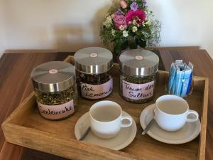 a wooden tray with three jars and cups and a vase of flowers at HAKs Alpine Studio Cozy Retreat Leukerbad in Leukerbad
