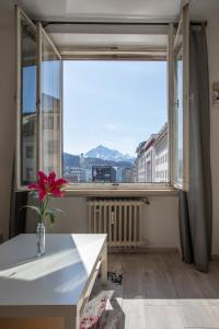 Pokój z dużym oknem ze stołem i kwiatem w obiekcie Apartment in the City Center w mieście Innsbruck