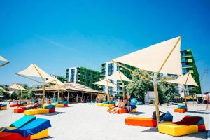 a group of chairs and umbrellas on a beach at LUXURY KLN Mamaia Nord in Mamaia Sat/Năvodari