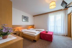 a hotel room with two beds and a red suitcase at Hotel Pension Rechtenthal in Termeno