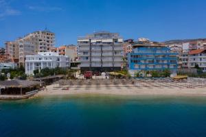 a beach with chairs and buildings and the water at Seaside Apartment in Sarandë