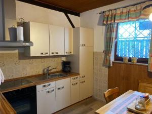 a kitchen with white cabinets and a sink and a table at Haus an der Bergwiese in Waldkirchen