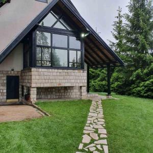 a house with a large window and a grass yard at Planinska kuća sa dvorištem in Zlatibor