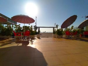 un patio con sillas rojas y sombrillas en la playa en Hotel Rancho del Mar, en Mojácar