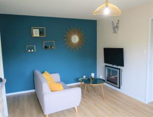 a living room with a couch and a blue wall at Appart'Confort - Le Trégor in Lannion