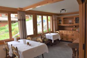 a dining room with two tables and windows at First Lodge in Grindelwald