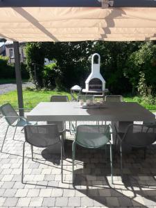 una mesa blanca y sillas bajo una sombrilla en Label Semois Gite rural 3 épis en Bouillon