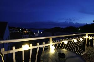 a glass table on a balcony at night at Tanya-Apartments and Rooms in Hvar