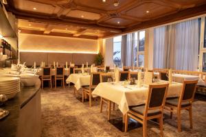 a restaurant with white tables and chairs and large windows at Hotel Charly in Ischgl