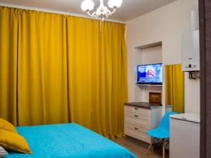 1 dormitorio con cortina amarilla y TV en La Casa Di Bury Apartments 2, en San Petersburgo