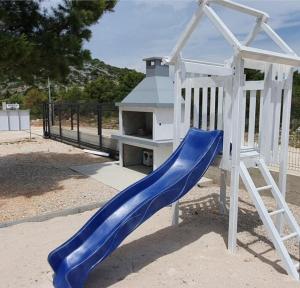 eine blaue Rutsche auf einem Spielplatz mit einer Bank in der Unterkunft BUQEZ Villa 30 "Beachvilla Stella" mit SPA & Meerblick in Drage