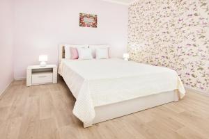 トリヤッチにあるPink Panther Apartment SUTKI LIFEの白いベッドと花の壁が備わるベッドルーム1室が備わります。